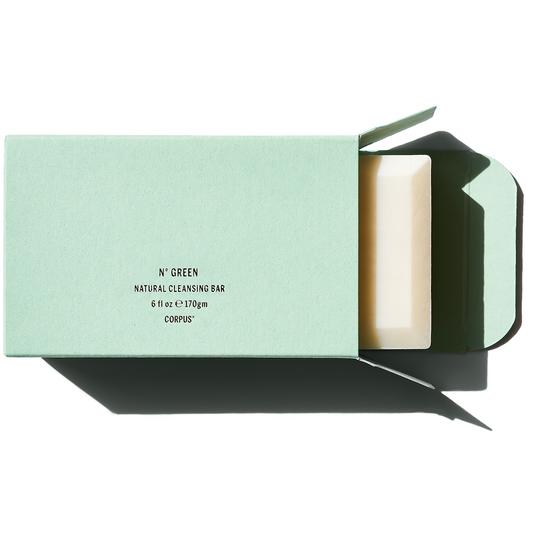 Natural cleansing bar in a green package, partially unwrapped, on a white background.